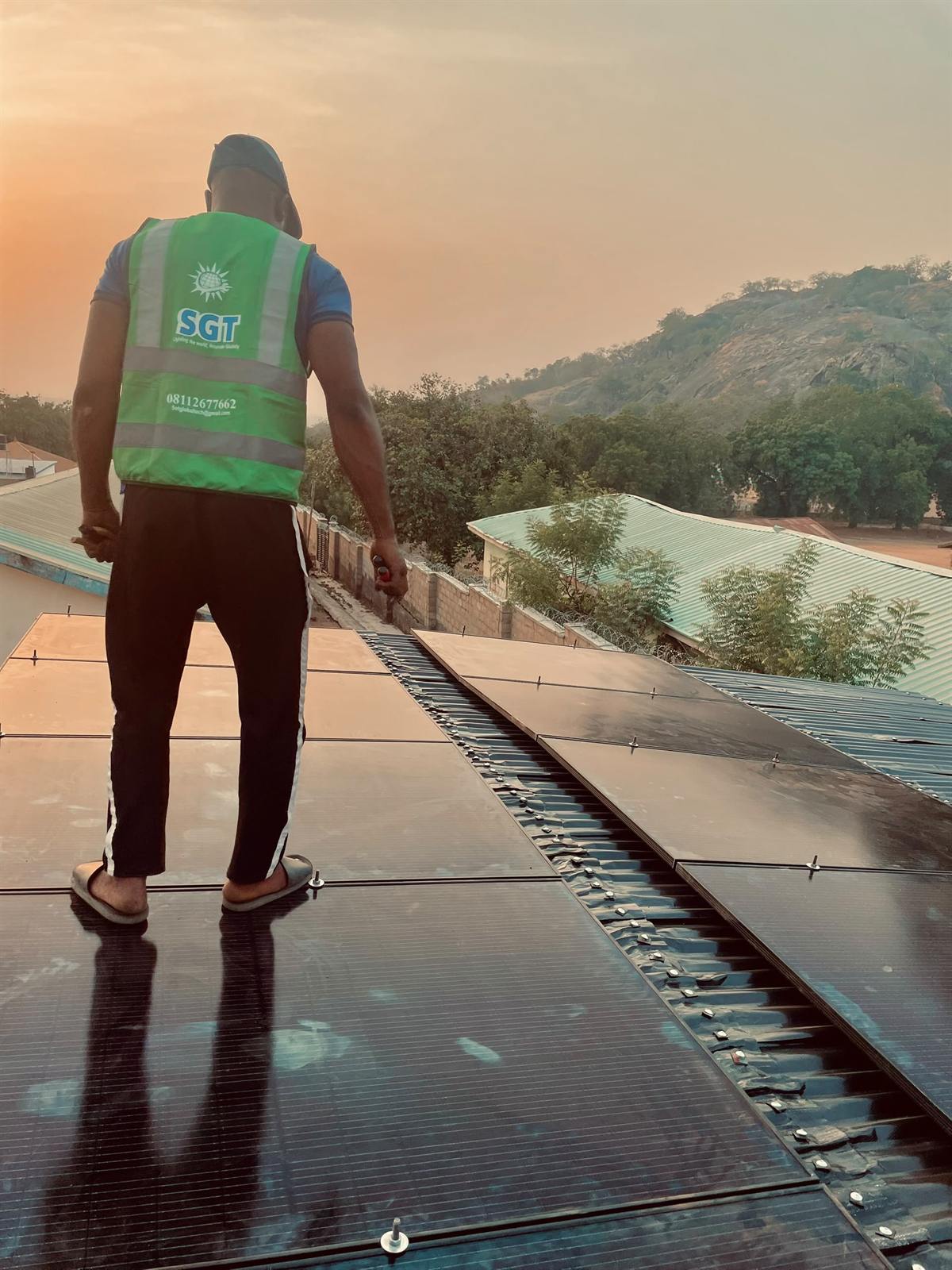 Installer standing on a finished solar array at sunset