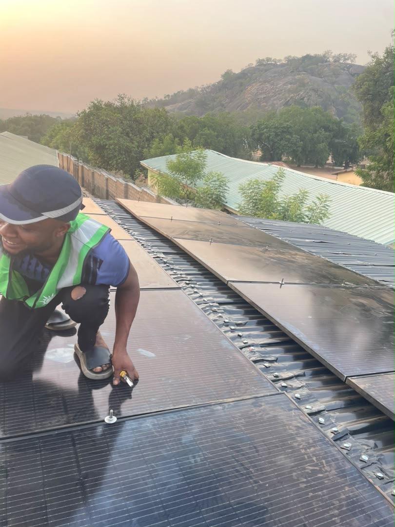 Installer fastening solar panels on a metal roof
