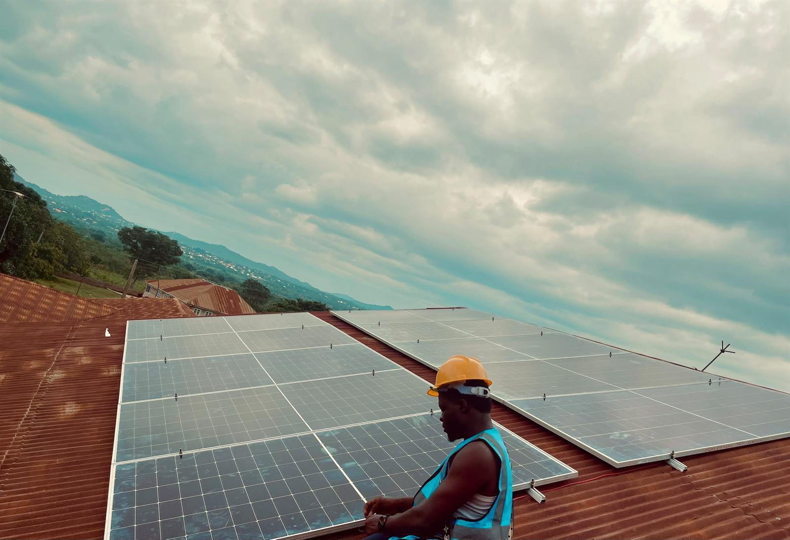Installer sitting beside a large rooftop solar array