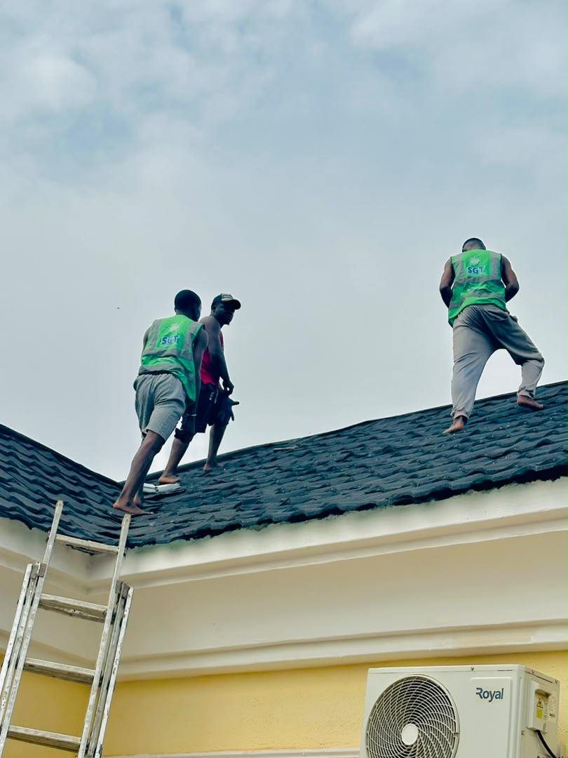 Three crew members standing on a rooftop ridge