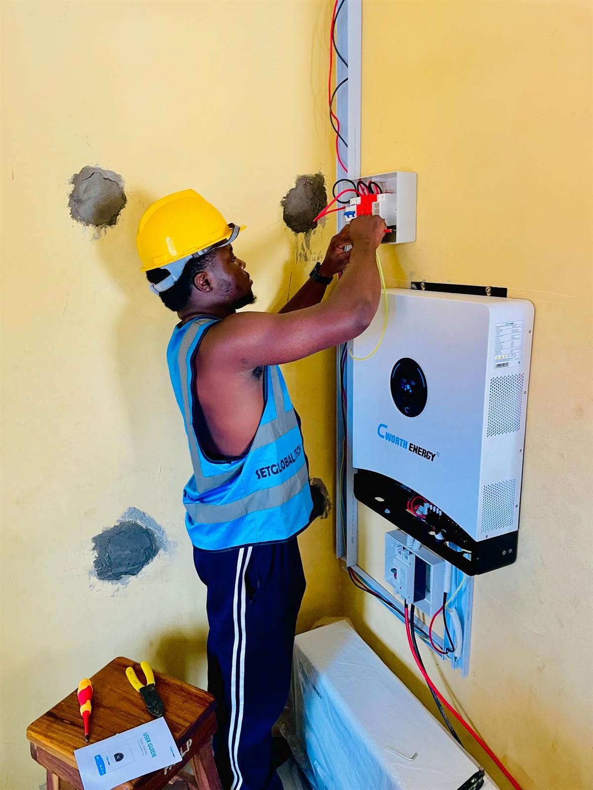 Installer in a SetGlobalTech vest wiring a hybrid inverter
